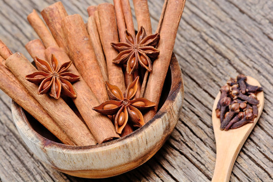 Heap of cinnamon sticks with anise star in a bowl and cloves