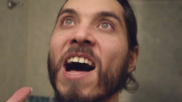 Furious yelling man in slow motion. Guy is angry he's making an evil screaming rage face.