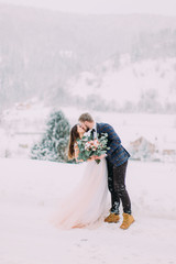 Winter love story. Beautiful couple in winter forest. Long-awaited meeting of two lovers. Young pretty pair of lovers. Winter. Date. A pair of lovers on a date in the mountains. 