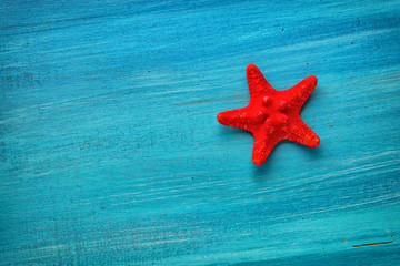 Summer board of red star fish on blue wooden background