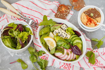Green salad, buddha bowl with tofu, vegetables, hummus with flax crispbread.