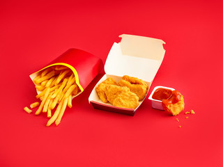 chicken nuggets and french fries on red background