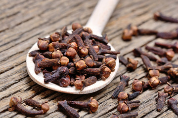 Wooden spoon with cloves on table