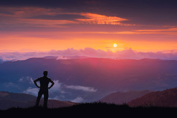 Silhouette of hiker on a hill against colorful majestic sunset