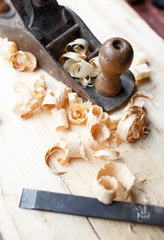Old plane on wooden board, carpentry tools with wood shavings