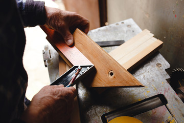 Old carpenter taking measurement of a wooden plank.