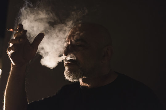 Silueta de fumador fumando de noche en el balc&oacute;n de un hogar