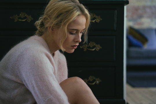 Young pensive woman sitting at home