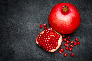 Pomegranate and seeds close-up on dark concrete background
