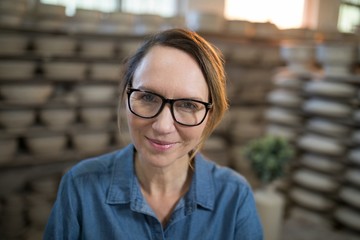 Happy female potter in pottery shop