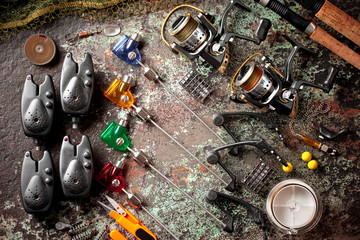 Fishing rods and spinnings in the composition with accessories for fishing on the old background on the table