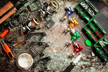 Fishing rods and spinnings in the composition with accessories for fishing on the old background on the table