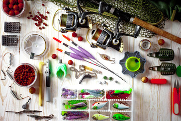 Fishing rods and spinnings in the composition with accessories for fishing on the old background on the table