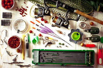 Fishing rods and spinnings in the composition with accessories for fishing on the old background on the table