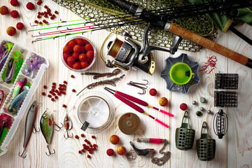 Fishing rods and spinnings in the composition with accessories for fishing on the old background on the table