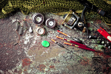 Fishing rods and spinnings in the composition with accessories for fishing on the old background on the table