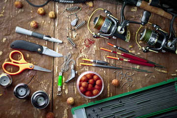 Fishing rods and spinnings in the composition with accessories for fishing on the old background on the table