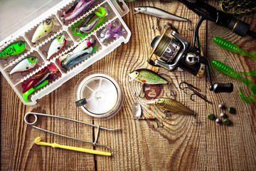 Fishing rods and spinnings in the composition with accessories for fishing on the old background on the table