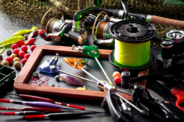 Fishing rods and spinnings in the composition with accessories for fishing on the old background on the table