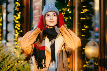 Blown away young woman injoying winter holiday while walking outdoor in winter city street. Christmas, new year, winter holidays concept.