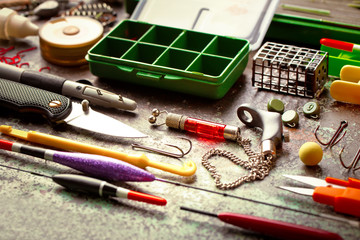 Fishing rods and spinnings in the composition with accessories for fishing on the old background on the table