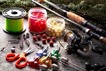 Fishing rods and spinnings in the composition with accessories for fishing on the old background on the table