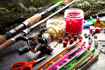 Fishing rods and spinnings in the composition with accessories for fishing on the old background on the table