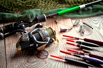 Fishing rods and spinnings in the composition with accessories for fishing on the old background on the table