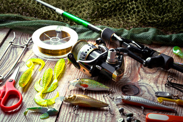 Fishing rods and spinnings in the composition with accessories for fishing on the old background on the table