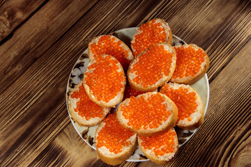 Sandwiches with butter and red caviar on wooden table