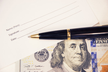 The signature form with a pen and a hundred dollars. Signing up business papers. Business.