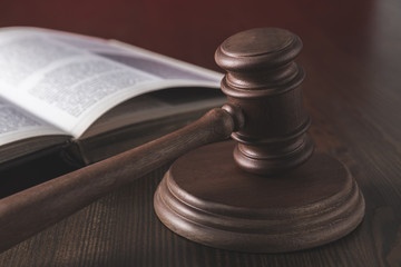 opened juridical book with hammer on wooden table, law concept