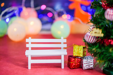 An empty white long bench with christmas tree on bokeh light
