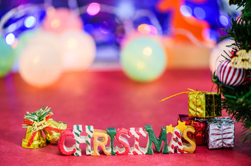 Fototapeta na wymiar Christmas letter decoration with christmas bells and presents on bokeh light