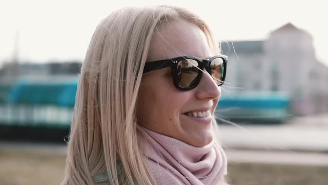 Portrait of beautiful blonde hair Caucasian woman. Happy smiling pretty young 20s girl in stylish sunglasses side view.
