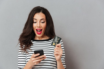 Fototapeta premium Portrait of an excited girl looking at mobile phone