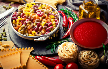 Raw pasta in the composition on the table with items for cooking