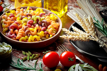 Raw pasta in the composition on the table with items for cooking