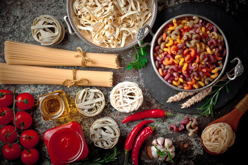 Raw pasta in the composition on the table with items for cooking