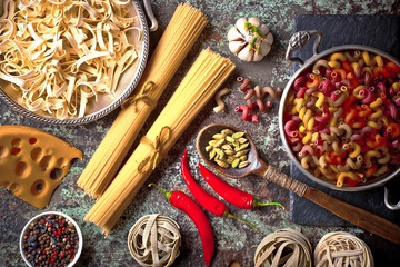 Raw pasta in the composition on the table with items for cooking