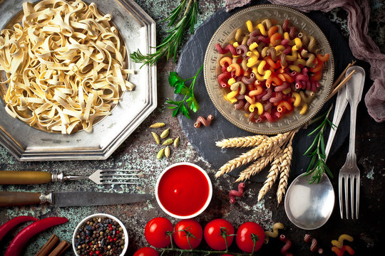 Raw pasta in the composition on the table with items for cooking