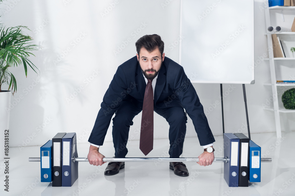 Wall mural businessman in suit weightlifting folders in office