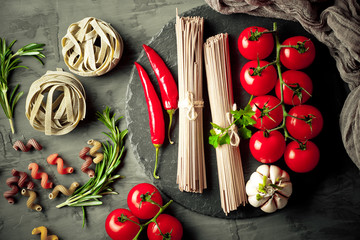 Raw pasta in the composition on the table with items for cooking