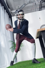 angry businessman in rugby helmet playing american football in office