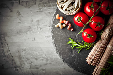 Raw pasta in the composition on the table with items for cooking