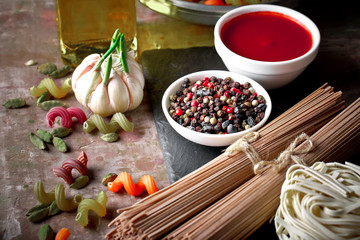 Raw pasta in the composition on the table with items for cooking