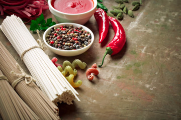Raw pasta in the composition on the table with items for cooking