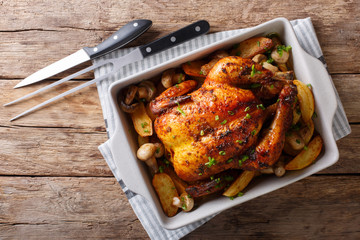 Tasty food: grilled chicken with mushrooms and potatoes close-up in a baking dish. Horizontal top view