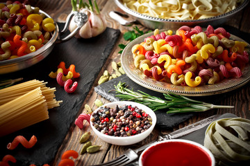 Raw pasta in the composition on the table with items for cooking