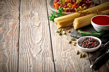 Raw pasta in the composition on the table with items for cooking